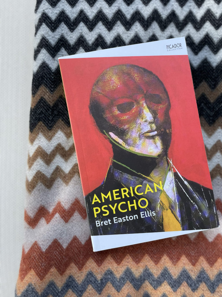 Boken American Psycho av Bret Easton Ellis liggende på Missoni pledd i høstlige farger