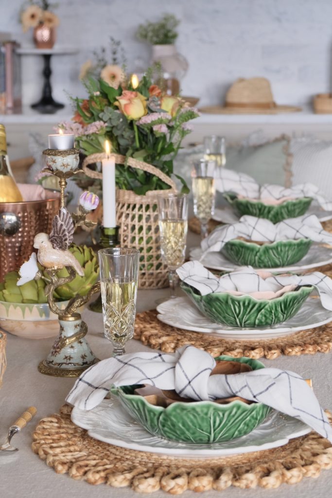 Vårlig borddekking med tallerker, servietter, linduk, stearinlys og dekorasjoner
